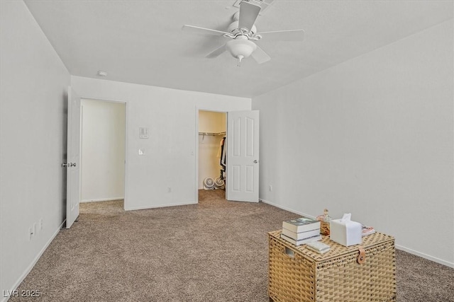 unfurnished bedroom featuring ceiling fan, a walk in closet, a closet, and carpet floors