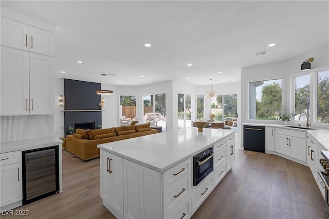 kitchen featuring sink, wine cooler, backsplash, and decorative light fixtures