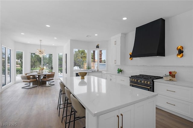 kitchen featuring white cabinetry, wall chimney exhaust hood, gas stove, and a kitchen island