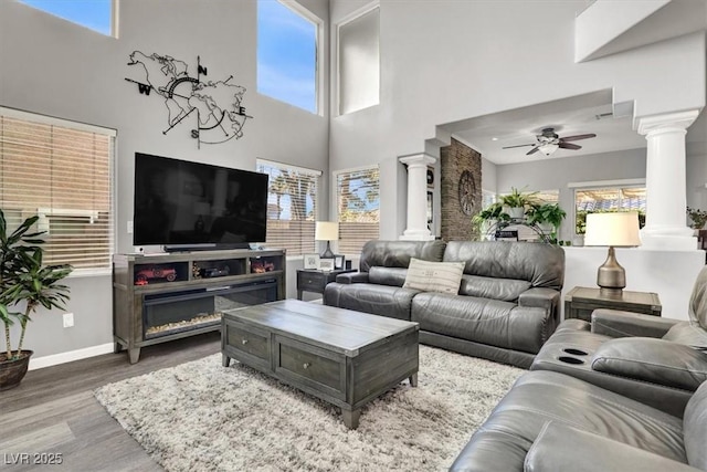 living room featuring ceiling fan, wood-type flooring, and ornate columns