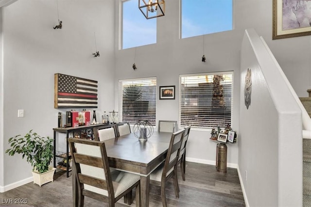 dining area with dark wood-type flooring and a towering ceiling