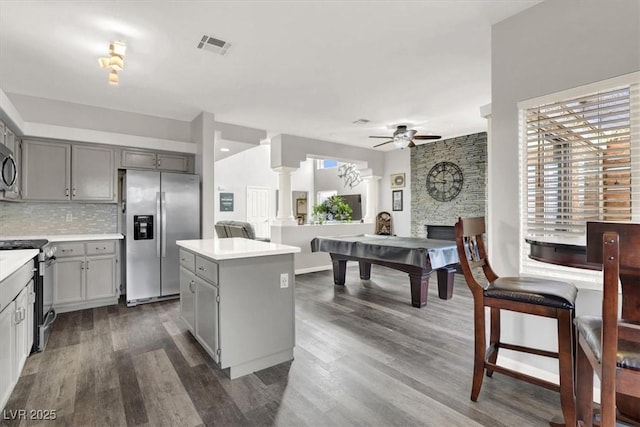 kitchen with tasteful backsplash, ceiling fan, gray cabinets, a center island, and appliances with stainless steel finishes