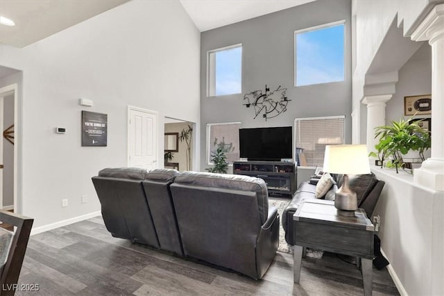 living room featuring a towering ceiling, dark hardwood / wood-style floors, and decorative columns