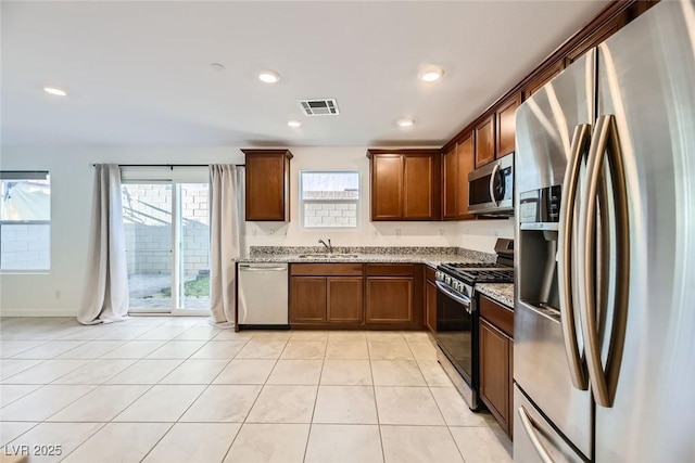 kitchen with sink, light stone counters, stainless steel appliances, and light tile patterned flooring