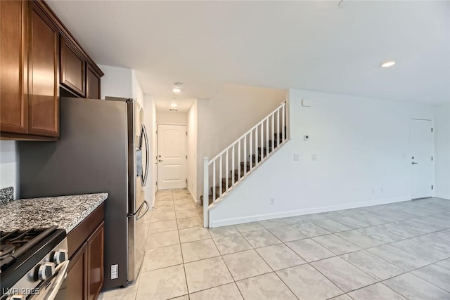 kitchen featuring light tile patterned floors, stainless steel appliances, and light stone countertops