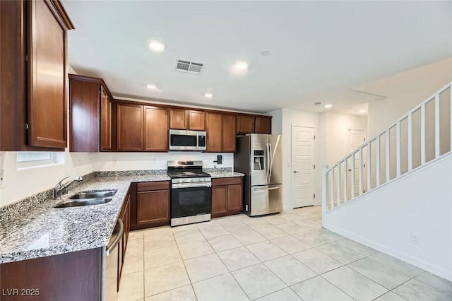 kitchen with light stone counters, sink, appliances with stainless steel finishes, and light tile patterned floors