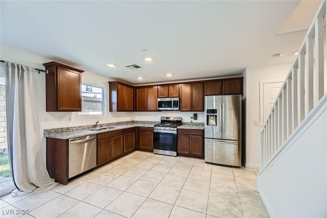 kitchen with sink, light stone counters, stainless steel appliances, and light tile patterned flooring