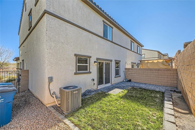 rear view of house featuring central AC unit and a yard