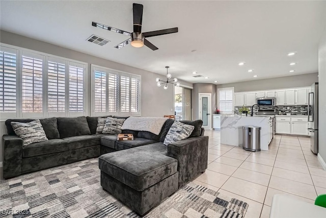 living room featuring light tile patterned floors, sink, and ceiling fan with notable chandelier