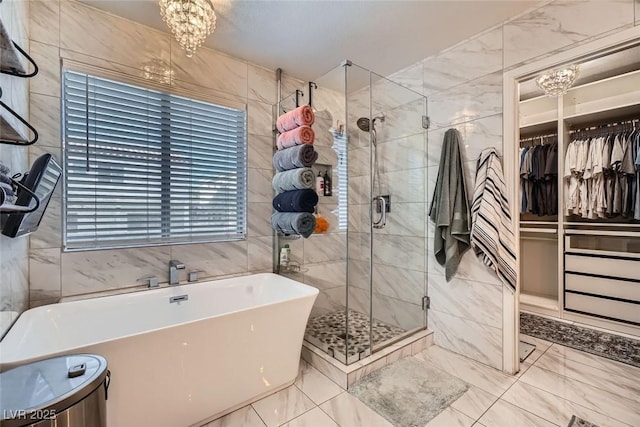 bathroom featuring shower with separate bathtub, tile walls, and a notable chandelier