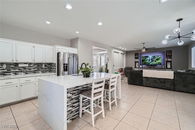 kitchen with white cabinetry, decorative backsplash, light tile patterned floors, a center island with sink, and high end refrigerator