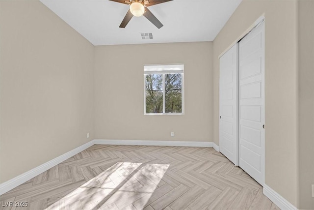 unfurnished bedroom featuring ceiling fan, a closet, and light parquet floors