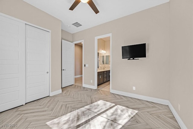 bedroom featuring a closet, light parquet floors, connected bathroom, and ceiling fan