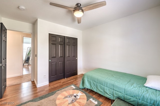 bedroom with a closet, hardwood / wood-style flooring, and ceiling fan