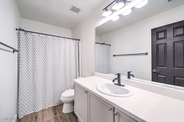 bathroom featuring toilet, walk in shower, wood-type flooring, and vanity