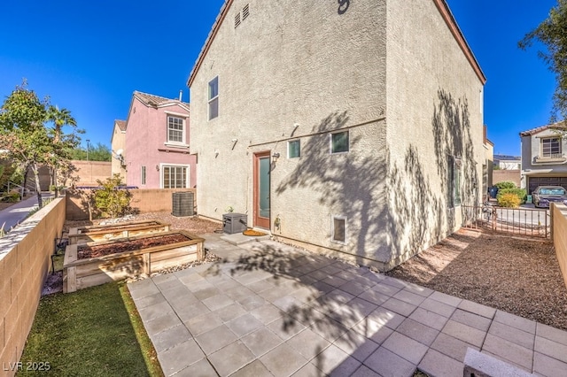 rear view of house with central AC unit and a patio