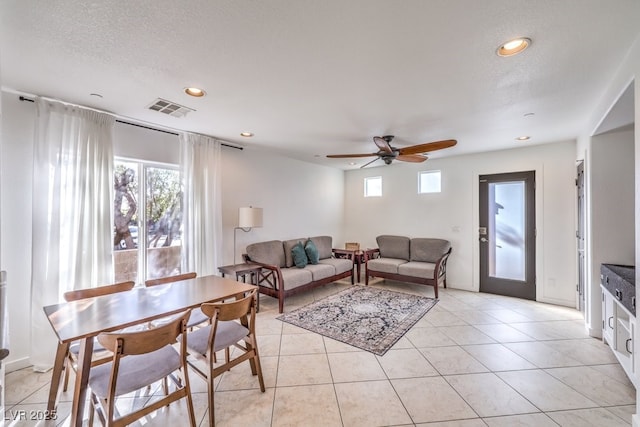 living room with ceiling fan, light tile patterned floors, a wealth of natural light, and a textured ceiling