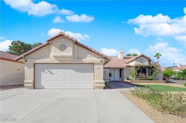 mediterranean / spanish house with driveway, a tile roof, a chimney, an attached garage, and stucco siding