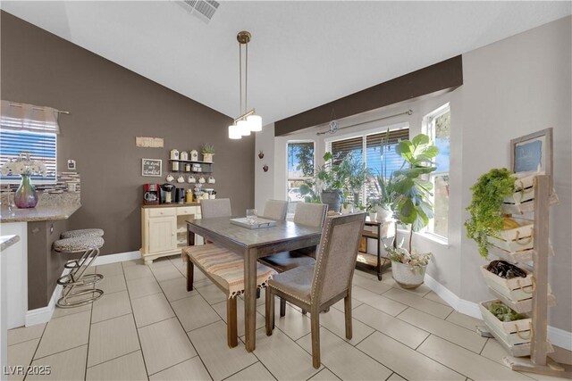 tiled dining area with plenty of natural light and vaulted ceiling