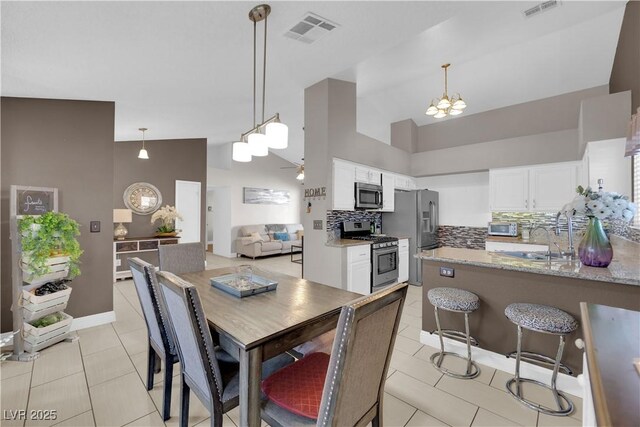 dining area featuring light tile patterned floors, sink, ceiling fan with notable chandelier, and high vaulted ceiling