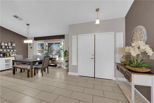 foyer entrance with vaulted ceiling, an inviting chandelier, and light tile patterned floors