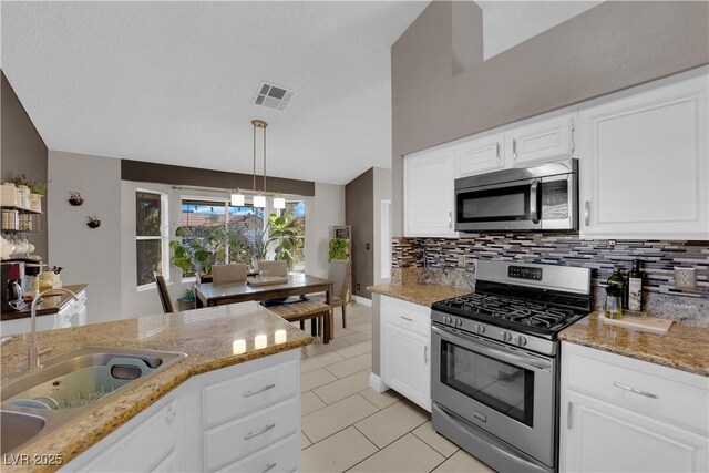 kitchen featuring light stone countertops, white cabinets, appliances with stainless steel finishes, sink, and hanging light fixtures