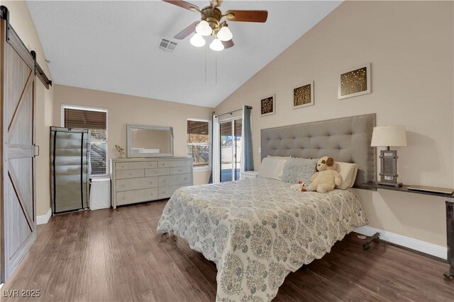 bedroom with ceiling fan, a barn door, vaulted ceiling, and hardwood / wood-style flooring