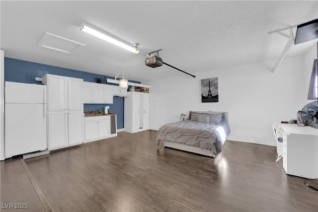 bedroom featuring dark wood-type flooring, a textured ceiling, and white refrigerator