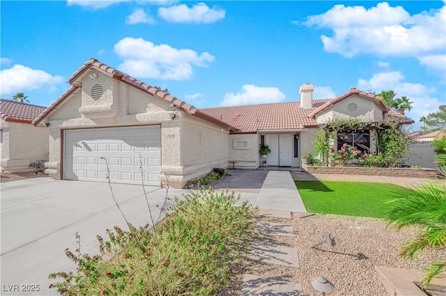 mediterranean / spanish home featuring stucco siding, concrete driveway, an attached garage, a chimney, and a tiled roof