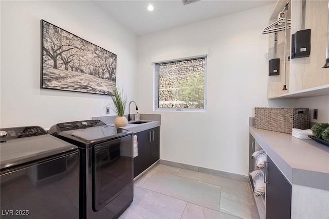 clothes washing area with light tile patterned floors, washing machine and dryer, sink, and cabinets