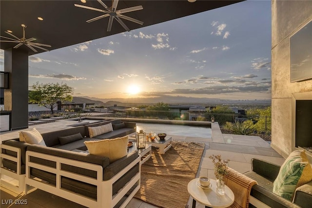 patio terrace at dusk featuring ceiling fan, an outdoor hangout area, and a water view