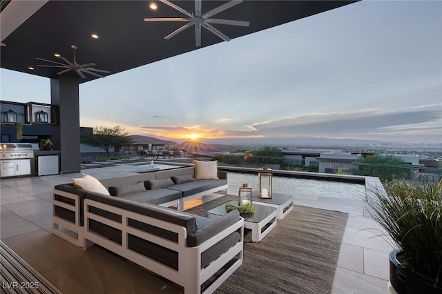 patio terrace at dusk with exterior kitchen, outdoor lounge area, and area for grilling