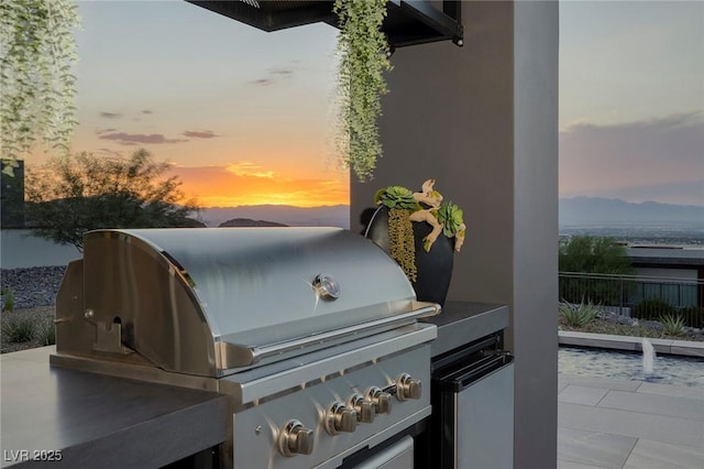 patio terrace at dusk featuring an outdoor kitchen and grilling area