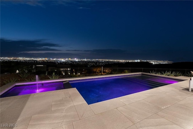 pool at night featuring pool water feature