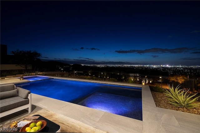 pool at twilight featuring an in ground hot tub