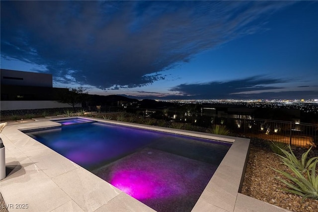 pool at dusk featuring an in ground hot tub