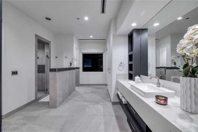 bathroom featuring a tile shower and vanity