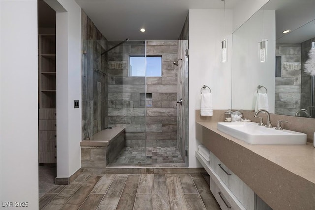 bathroom featuring a shower with shower door and vanity