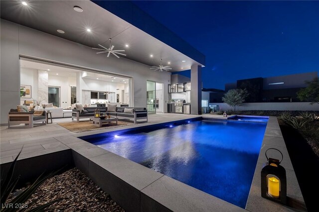 pool at night with ceiling fan and an in ground hot tub