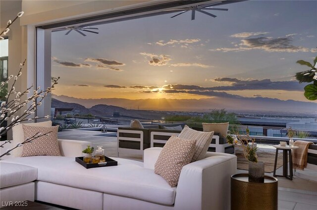 patio terrace at dusk with ceiling fan, a mountain view, and an outdoor hangout area