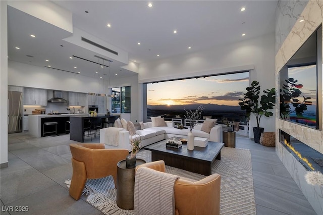 living room with recessed lighting, a high ceiling, and a tile fireplace