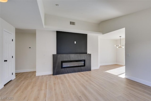 unfurnished living room with light hardwood / wood-style flooring and an inviting chandelier