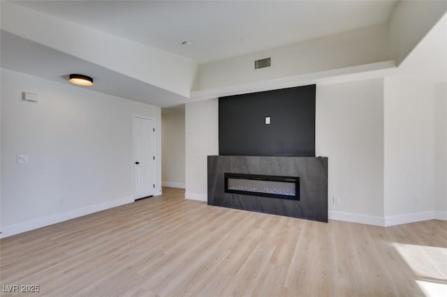 unfurnished living room featuring a raised ceiling and light hardwood / wood-style floors