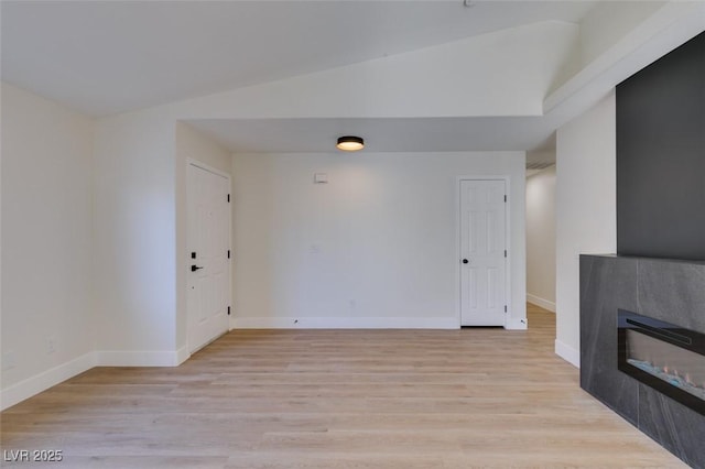 unfurnished living room with light wood-type flooring, a fireplace, and vaulted ceiling