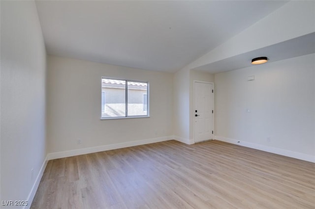 spare room featuring light hardwood / wood-style floors and lofted ceiling