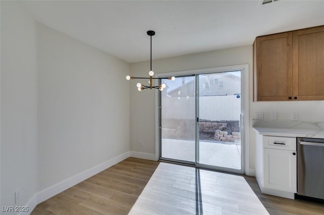 unfurnished dining area featuring light wood-type flooring and a chandelier