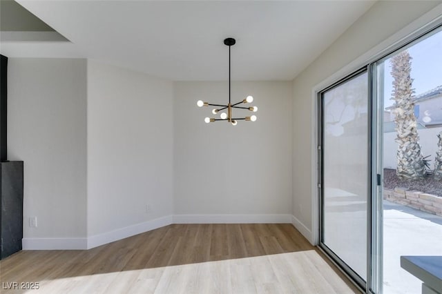 spare room with light hardwood / wood-style flooring and a notable chandelier