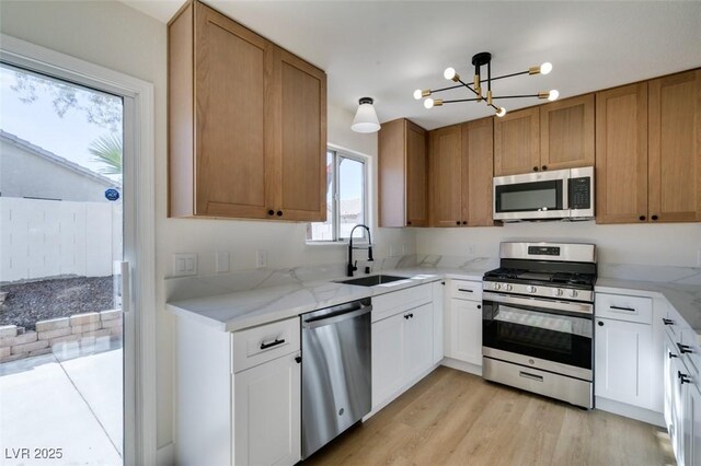 kitchen featuring light hardwood / wood-style floors, sink, white cabinetry, stainless steel appliances, and a chandelier