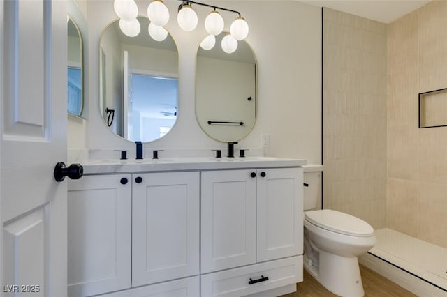 bathroom with toilet, vanity, hardwood / wood-style flooring, and a tile shower