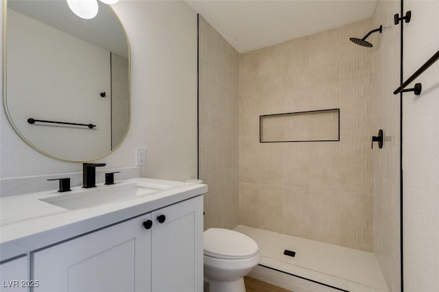 bathroom with toilet, vanity, and tiled shower